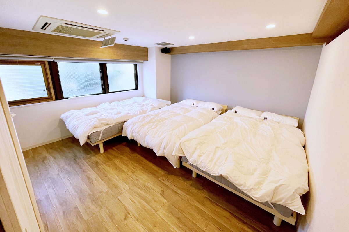 A room with two beds, a window, and a ceiling fan.