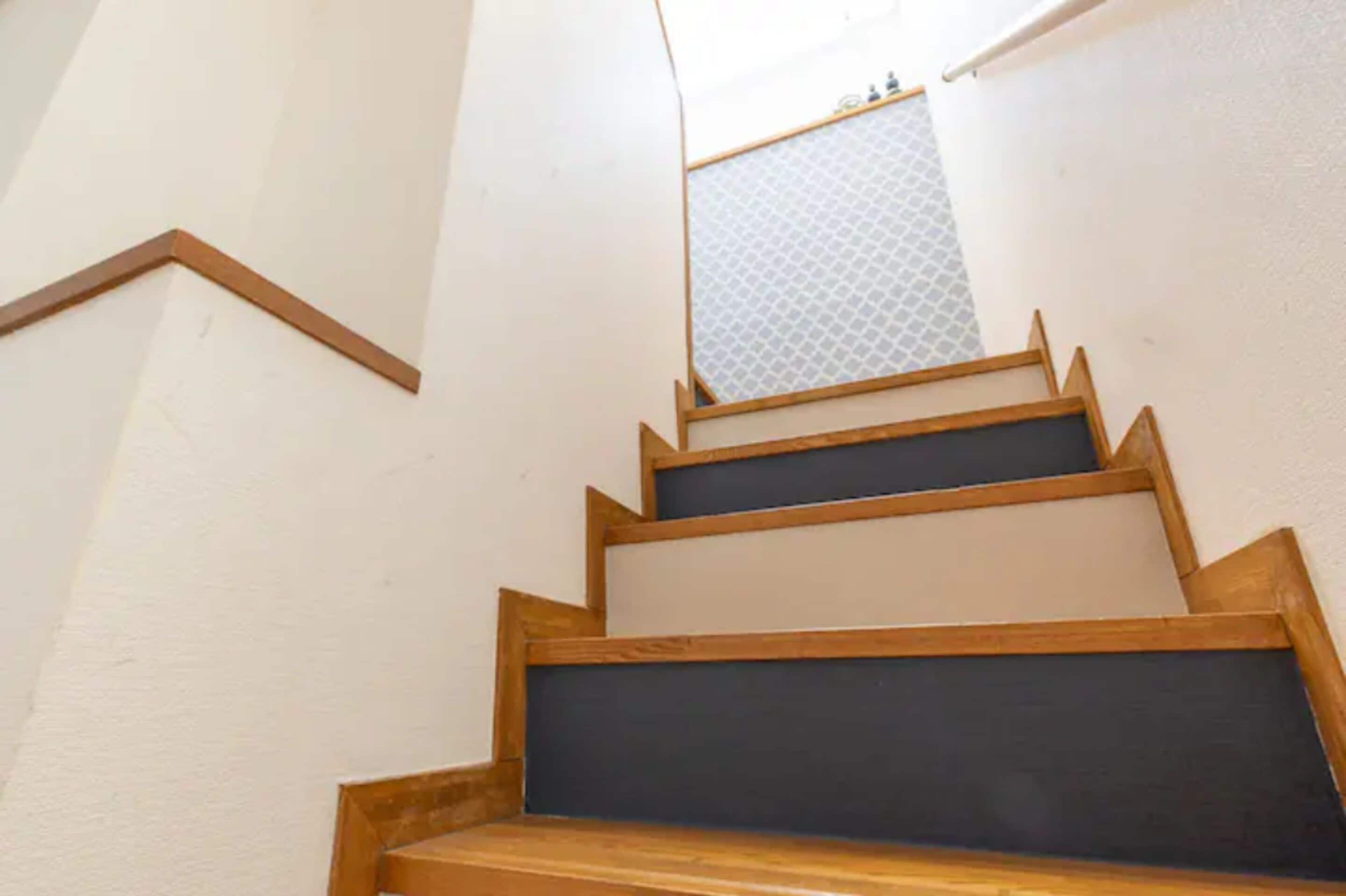 Un conjunto de escaleras de madera con escalones oscuros y paredes blancas.