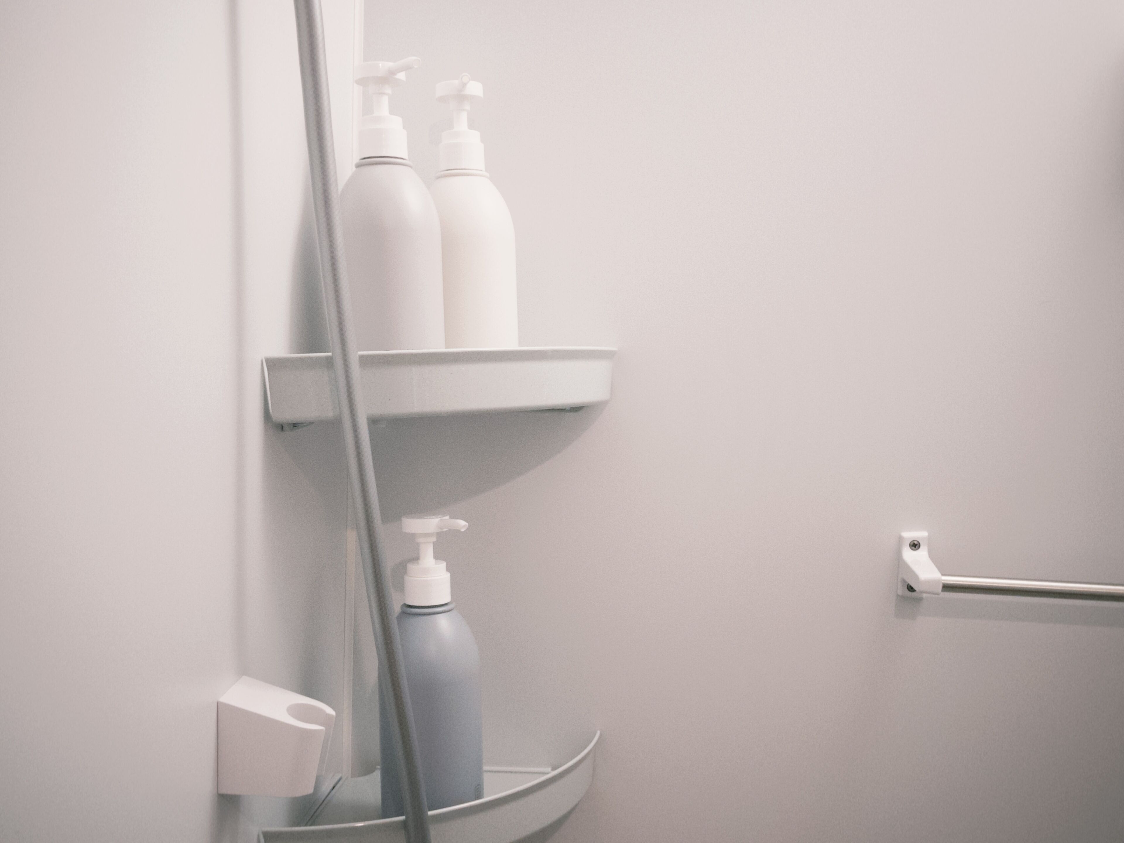 A bathroom with white shelves holding toiletries, a hand dryer, and a towel rack.