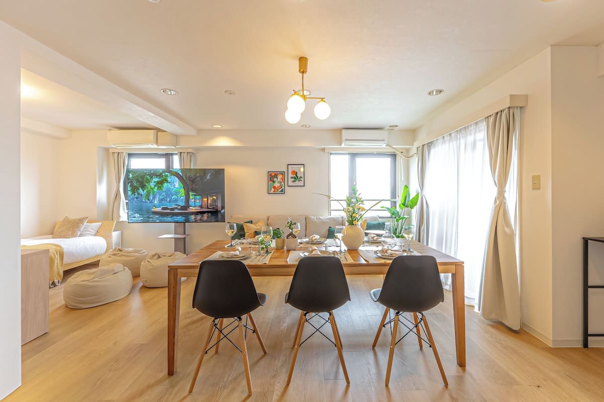 A modern living room with a dining area, a sofa, a TV, and a large window.