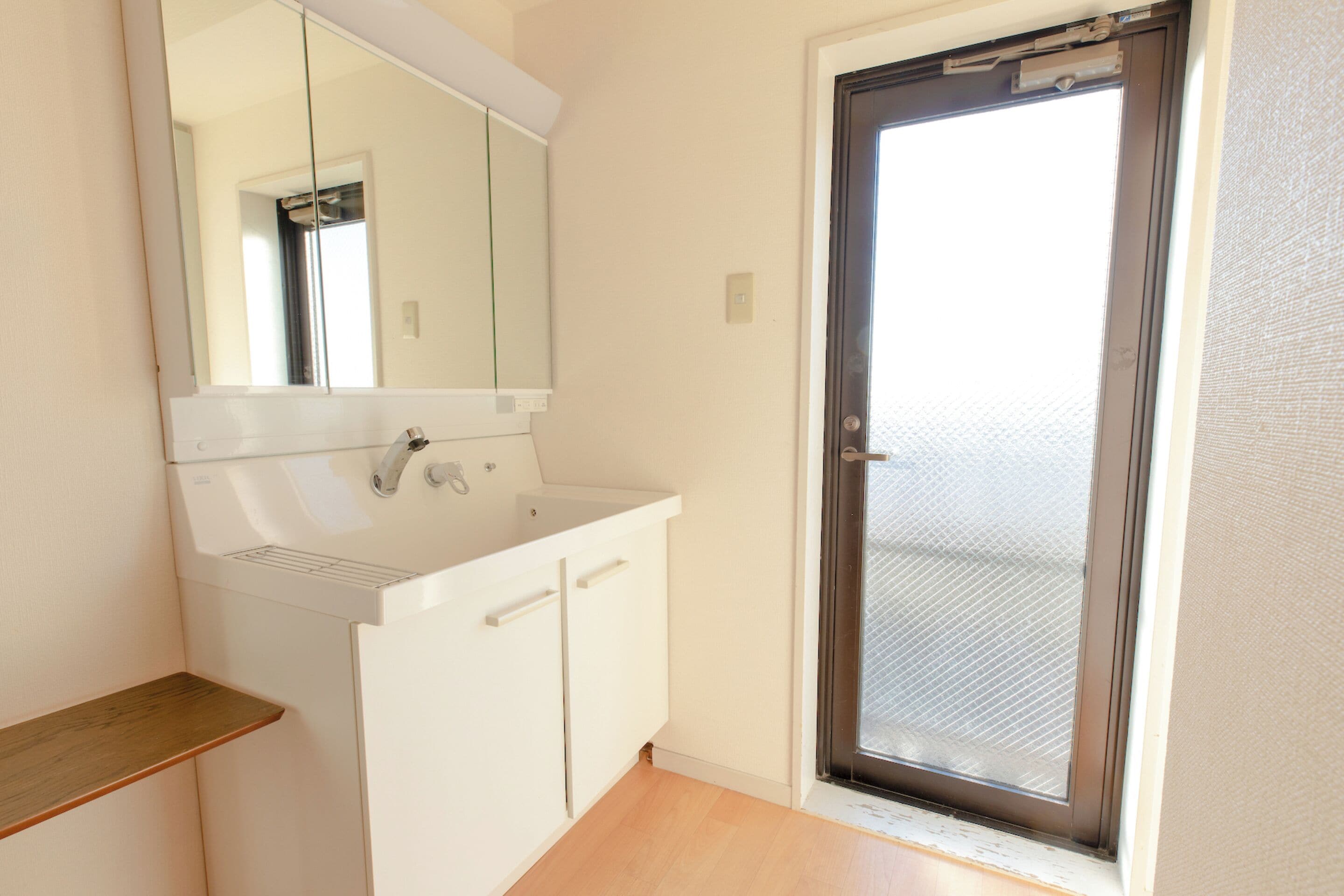 A small, clean bathroom with a white sink, mirror, and cabinet.