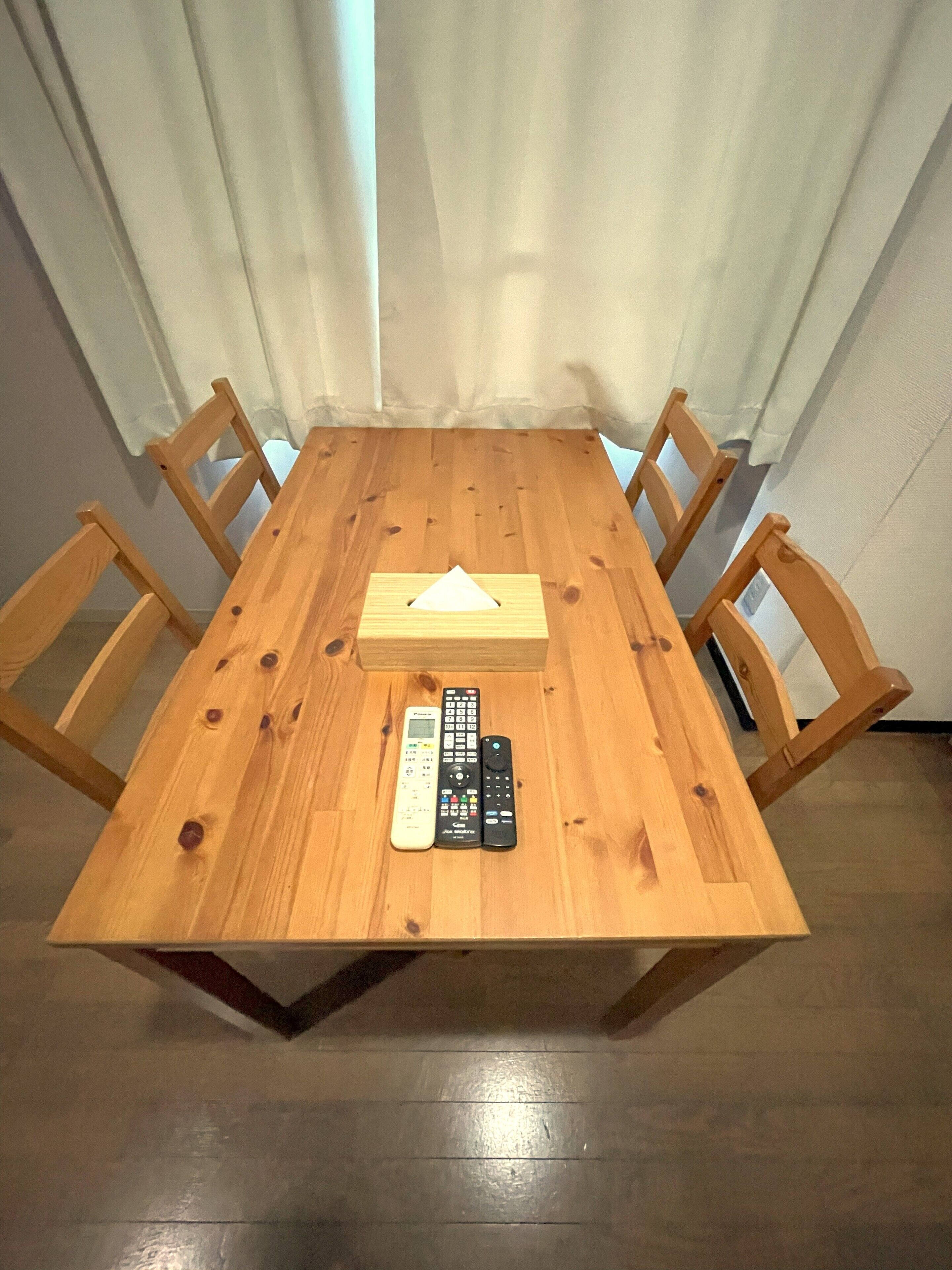 Ein Holztisch mit einer Kiste und drei Fernbedienungen.