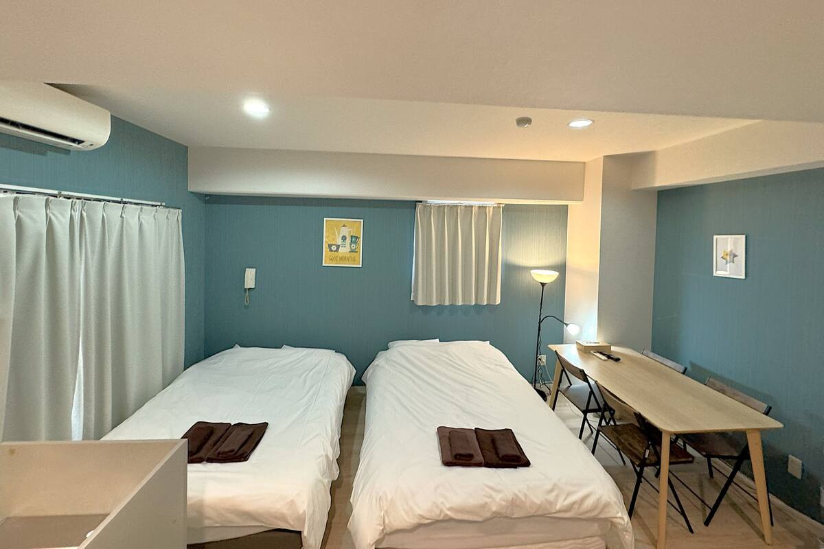 A hotel room with two single beds, a desk, and a chair.