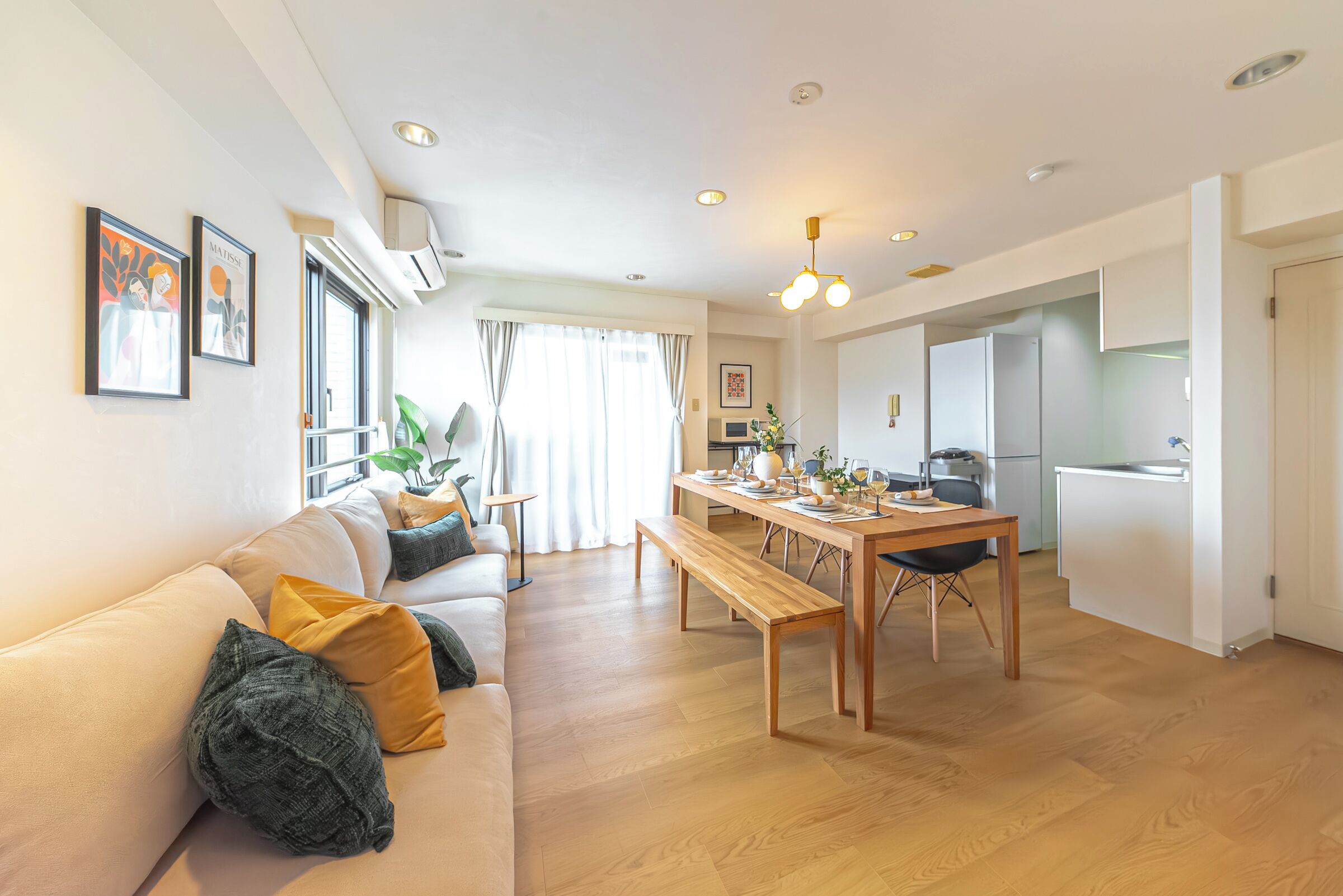 A modern living room with a sofa, dining table, and kitchen area.