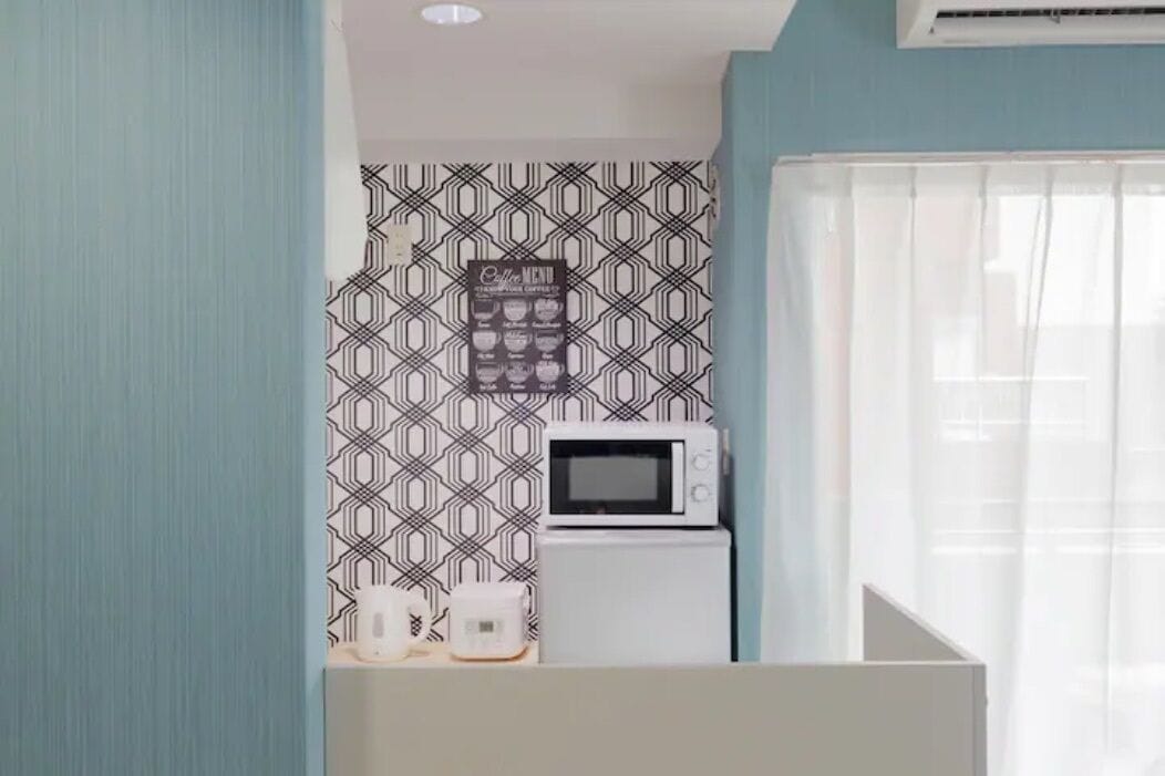 A small kitchenette with a microwave, a coffee maker, and a coffee menu on the wall.