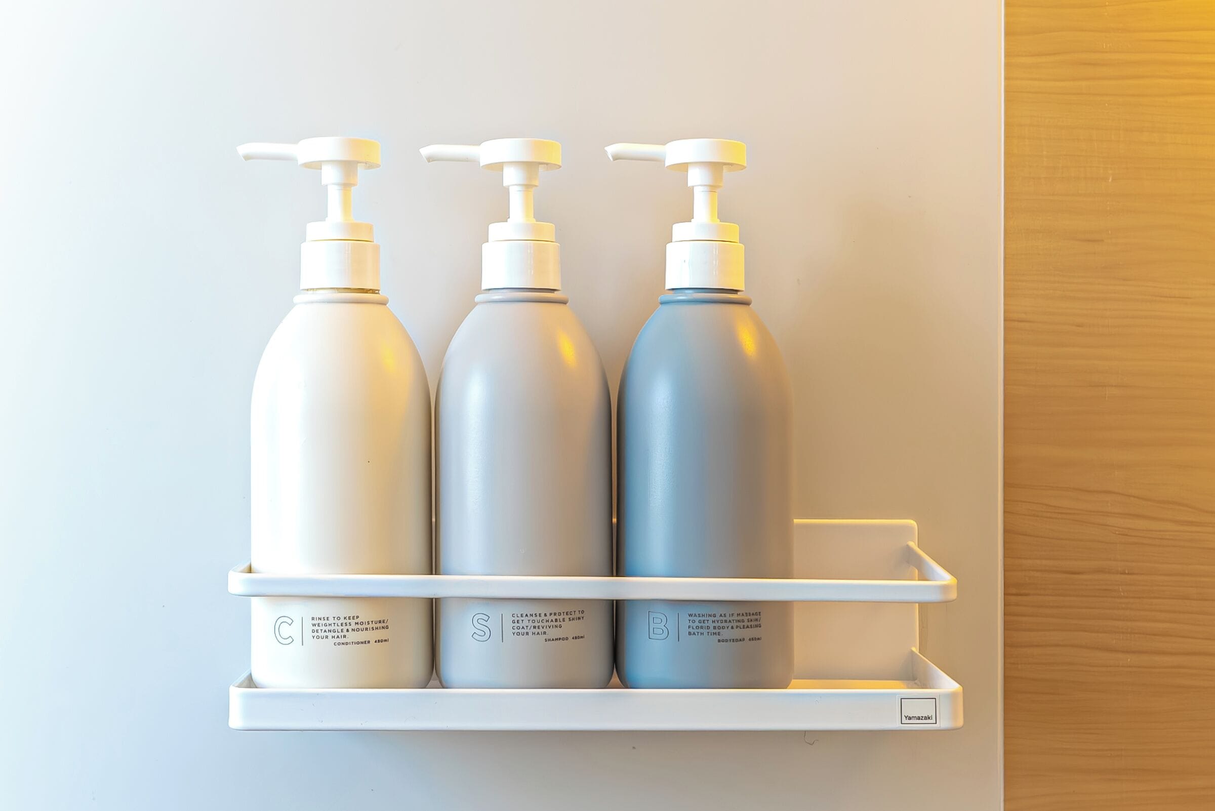 En hylde med tre flasker shampoo og conditioner.