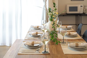 A dining table set with plates, cutlery, glasses, and a vase with flowers. - Grandioso Nakano Fujimicho (Tokyo)