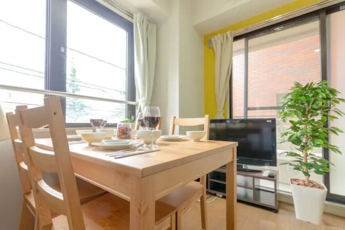 A dining area with a wooden table, chairs, a television, and a potted plant.