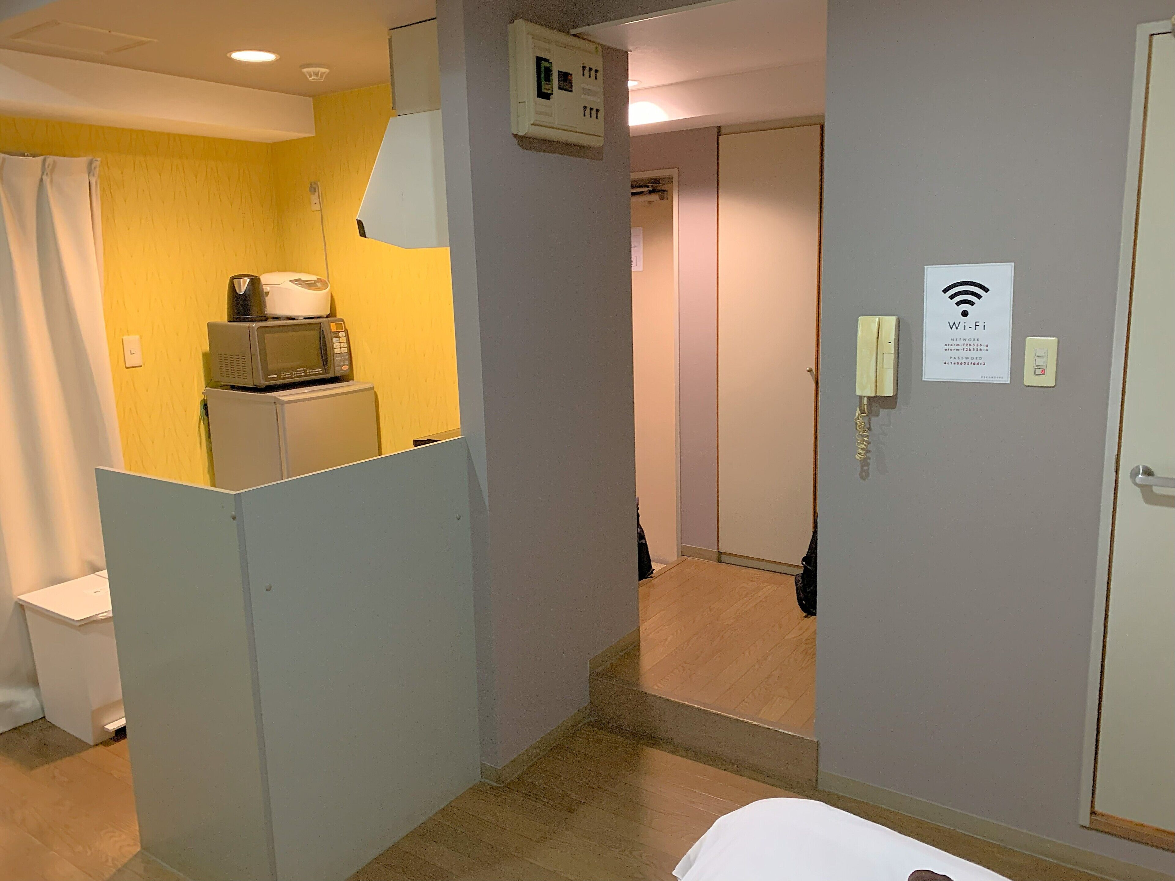 Une chambre d’hôtel équipée d’une kitchenette, d’un espace douche et d’une porte sur laquelle est apposé un symbole indiquant la présence du Wi-Fi.