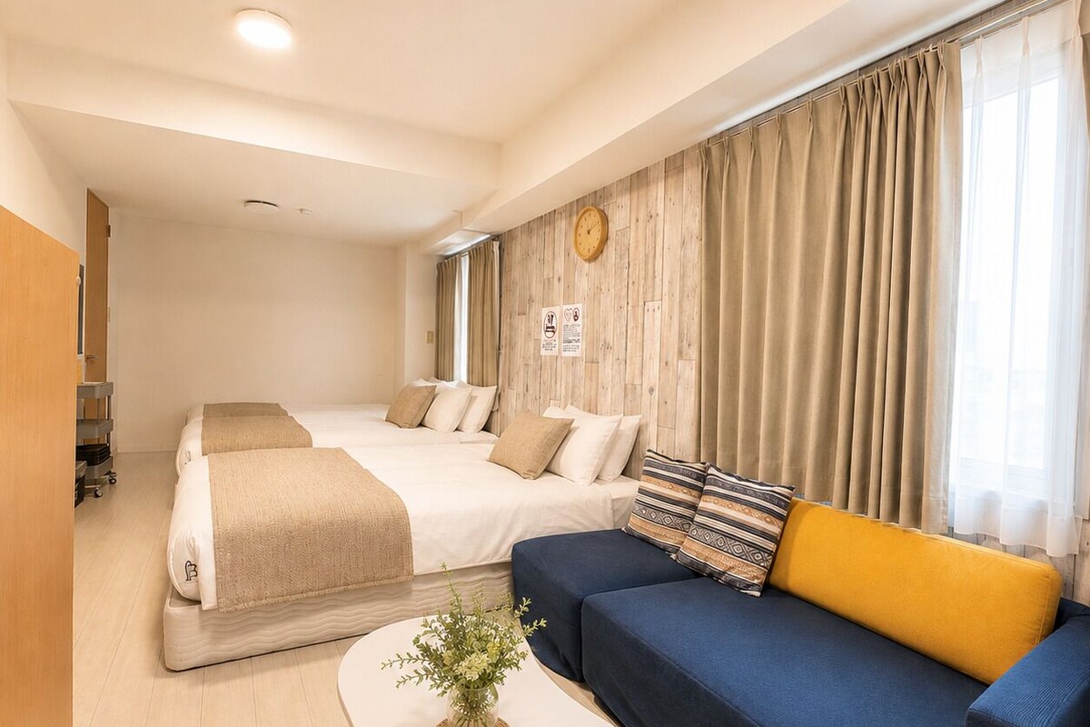 A hotel room with a bed, a sofa, a coffee table, and a clock on the wall.