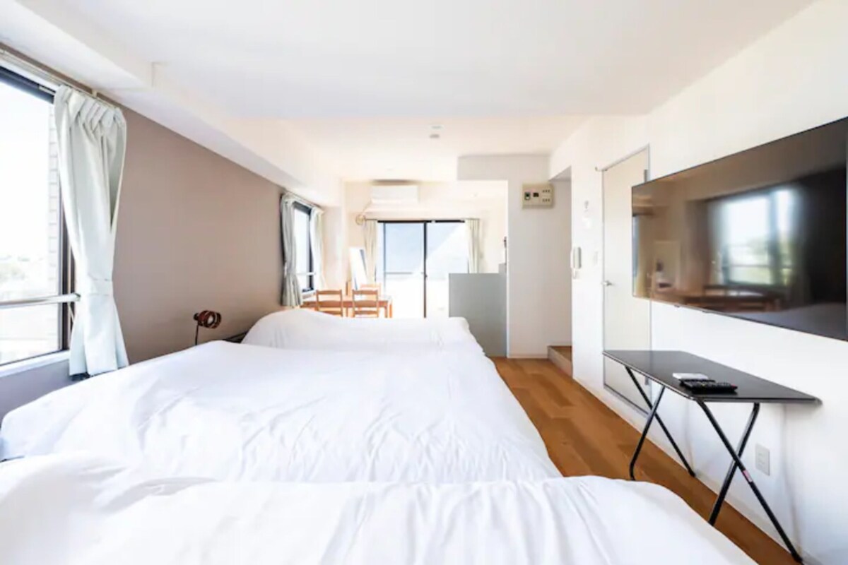 A hotel room with a large bed, a desk, a flat-screen TV, and a view of the outdoors.