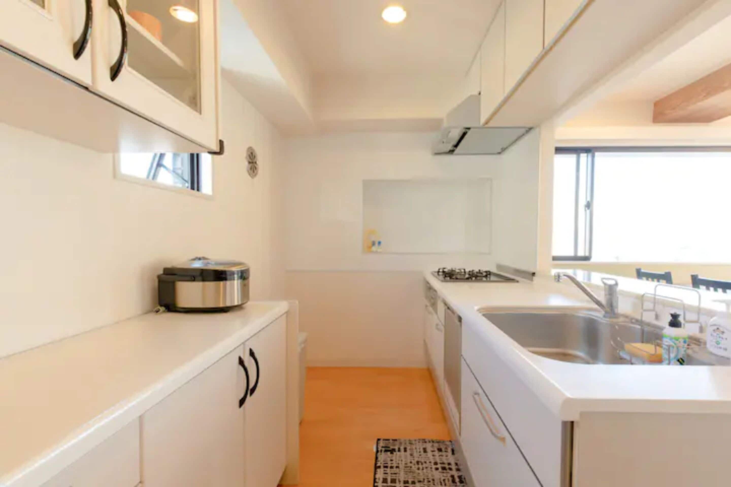 A compact kitchen with white cabinetry, a built-in oven, a sink, and a window providing natural light.