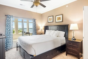 A bedroom with a bed, two bedside lamps, a nightstand, a desk, and a window with curtains.