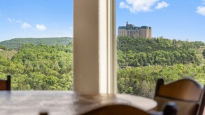 Blick aus einem Fenster auf eine üppige grüne Landschaft mit einem großen Gebäude auf einem Hügel.