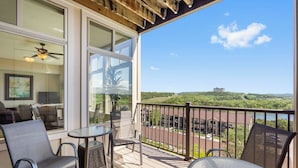 Ein Balkon mit Blick auf eine grüne Landschaft und ein entferntes Gebäude.