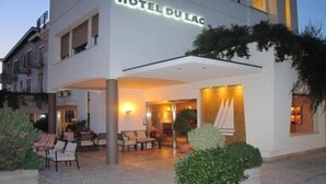 A hotel with a modern facade, a covered outdoor seating area, and a sign that reads "HOTEL DU LAC". - Du Lac Hotel (Sirmione)