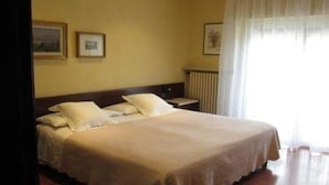 A hotel room with a bed, a nightstand, and a window with curtains. - Du Lac Hotel (Sirmione)