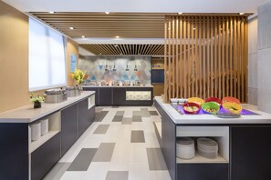A modern kitchen with a central island, a buffet setup, and a decorative wall. - Holiday Inn Express Foshan Chancheng (Foshan)