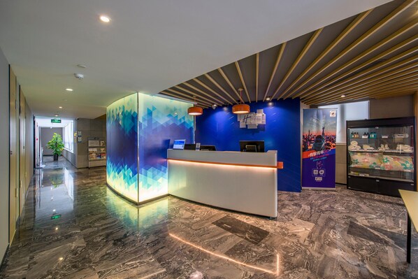 Un'area reception di un hotel dal design moderno, con una scrivania e una teca in vetro.