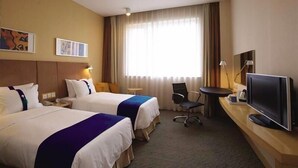 A hotel room with two beds, a desk with a TV, a chair, and a window with curtains. - Holiday Inn Express Foshan Chancheng (Foshan)
