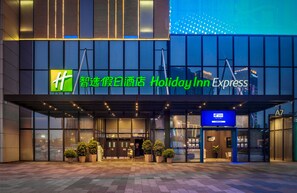 A Holiday Inn Express hotel entrance with a modern design, large windows, and potted plants. - Holiday Inn Express Foshan Chancheng (Foshan)