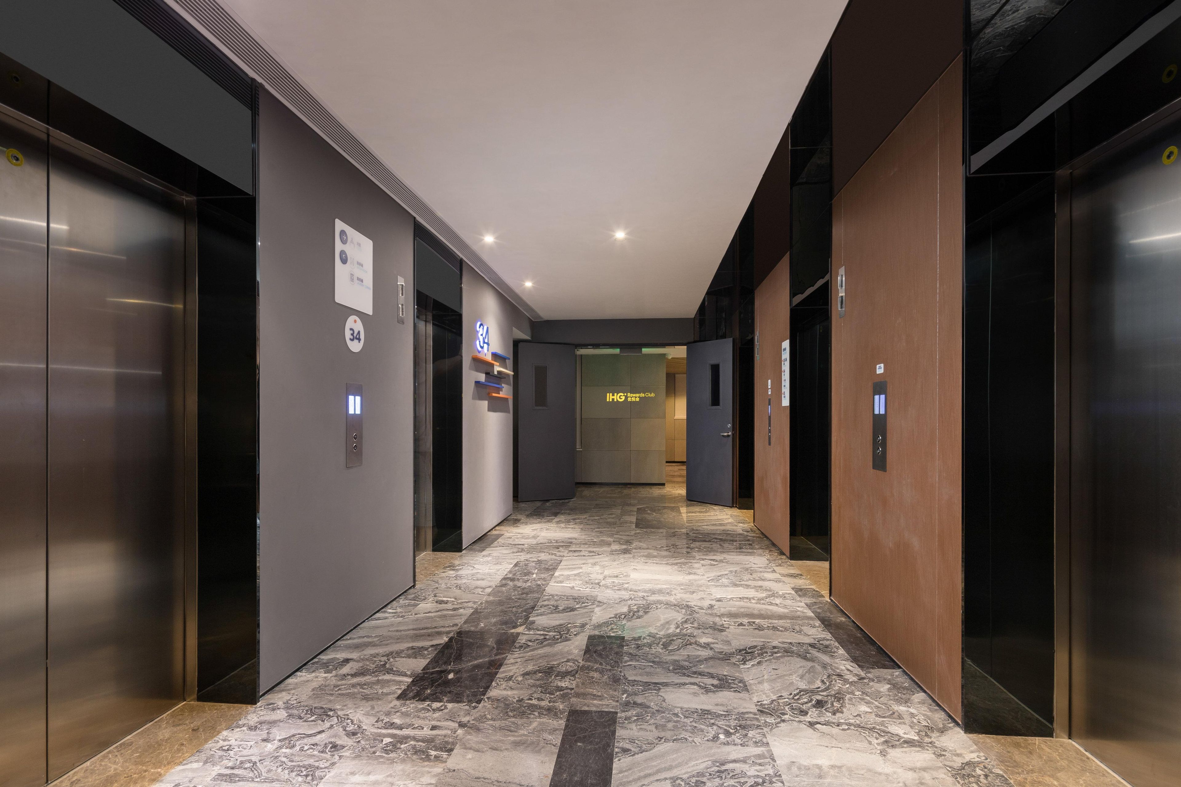 A modern elevator lobby with marble flooring, metallic elevator doors, and a sign indicating the location.