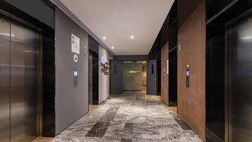 A modern elevator lobby with marble flooring, metallic elevator doors, and a sign indicating the location.