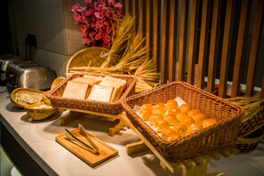 A buffet setup with bread, butter, and orange slices.