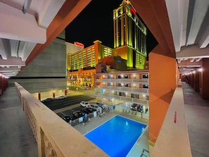 Un hotel con piscina, varios pisos y una torre destacada.