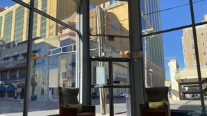 A hotel lobby with large windows, two armchairs, and a glass door entrance. - Clarion Inn Atlantic City - Beach and Boardwalk (Atlantic City)