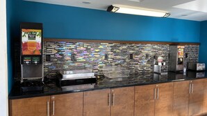 A modern kitchen with a blue wall, a mosaic backsplash, and a coffee machine. - Clarion Inn Atlantic City - Beach and Boardwalk (Atlantic City)