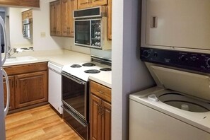 A compact kitchen with wooden cabinets, a stainless steel stove, a microwave, and a built-in washing machine. - Clarion Inn Atlantic City - Beach and Boardwalk (Atlantic City)