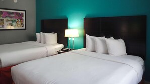 A hotel room with two beds, a nightstand with a lamp, and a painting on the wall. - Clarion Inn Atlantic City - Beach and Boardwalk (Atlantic City)