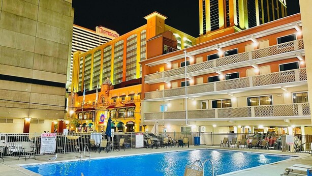 A hotel pool area with multiple levels of balconies, a sign for Tropicana, and a notice about no lifeguard on duty. - Clarion Inn Atlantic City - Beach and Boardwalk (Atlantic City)