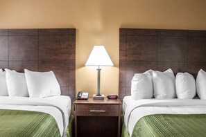 Een hotelkamer met twee bedden, een nachtkastje met een lamp, een telefoon en een digitale klok.