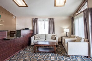 Een hotel lobby met een receptiebalie, een bank, een bijzettafeltje en een kamerbreed tapijt.