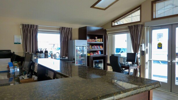A kitchen area with a refrigerator, a coffee machine, a microwave, and a dining table with chairs. - Quality Inn (Ontario)