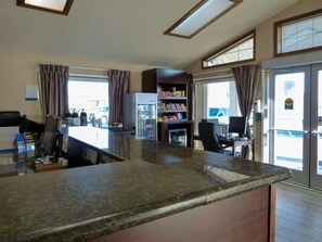 A kitchen area with a refrigerator, a coffee machine, a microwave, and a dining table with chairs. - Quality Inn (Ontario)