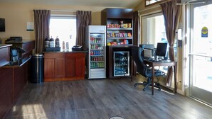A small kitchenette with a refrigerator, a coffee machine, and a trash bin. - Quality Inn (Ontario)