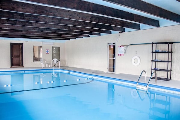 Una piscina interior amb aigua cristal·lina, una escala i un bou salvavides.