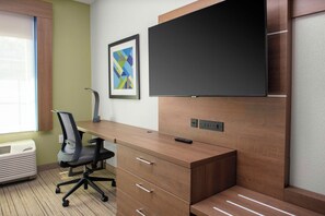 Un espacio de oficina moderno con un escritorio de madera, una silla de oficina negra, un televisor de pantalla plana montado en la pared y una obra de arte abstracta enmarcada.