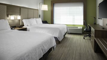 A hotel room with two beds, a desk, a chair, a TV, and a large window with blinds.
