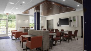 A modern restaurant with booths and tables, a wooden ceiling, and a large window overlooking greenery. - Holiday Inn Express Wells-Ogunquit-Kennebunk by IHG (Wells)