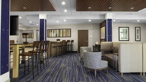 Eine moderne Hotellobby mit blauem Teppich, Holzzapfeln an der Decke, einem Essbereich mit Stühlen und einer Sitzecke mit Polstermöbeln.
