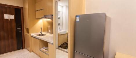 A compact kitchen with a built-in refrigerator, a sink, and a microwave.