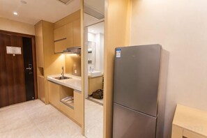 A compact kitchen with a built-in refrigerator, a sink, and a microwave. - Sweetome Boutique Apartment (Yangzhou Railway Station Jinghua City) (Yangzhou)