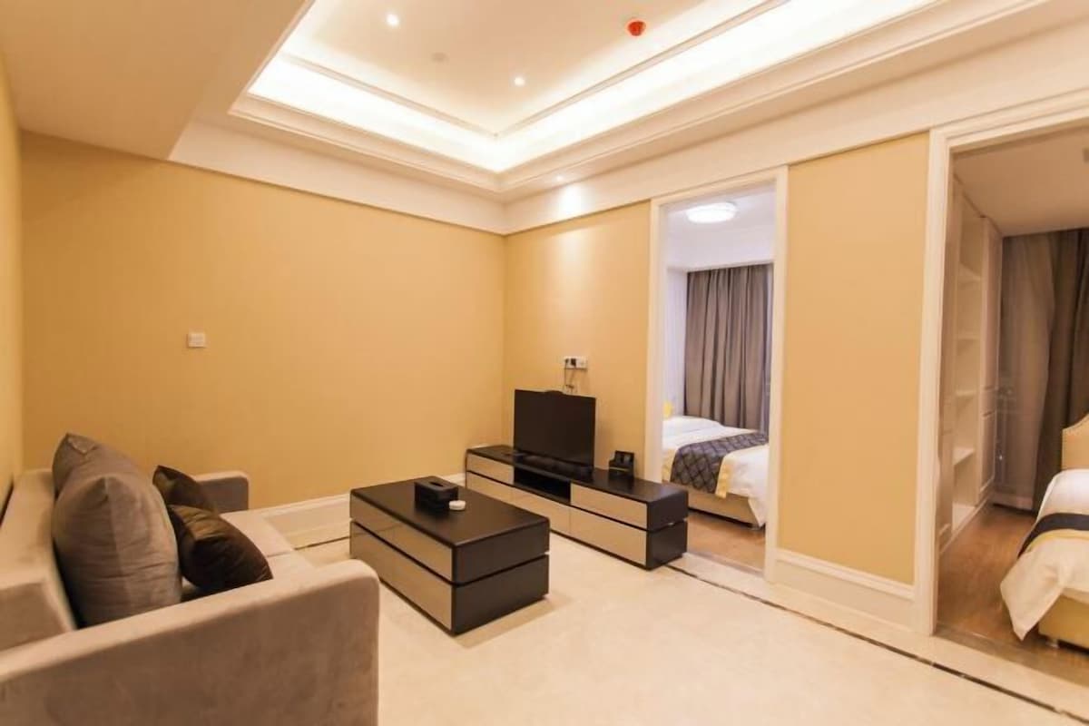 Ein Hotelzimmer mit Sofa, Fernseher, Nachttisch und Bett.