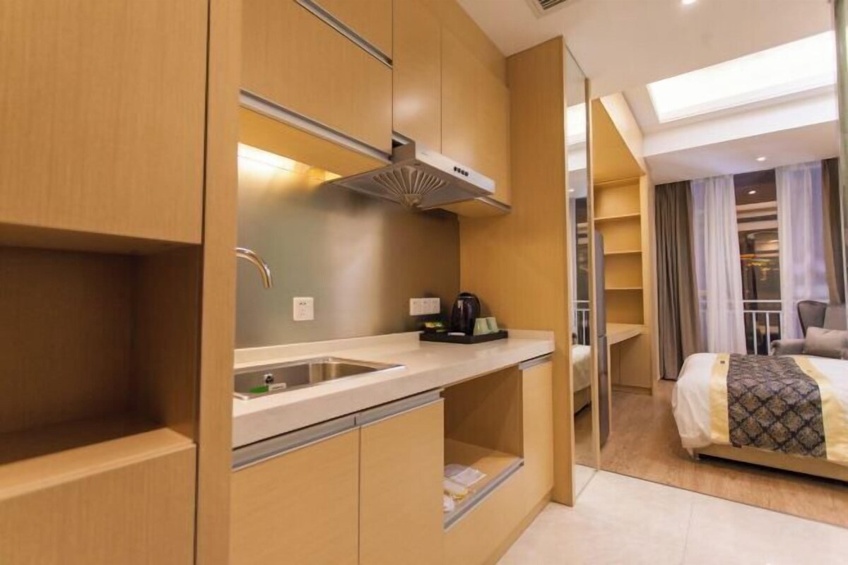 Ein kompaktes Hotelzimmer mit Küchenzeile, einem Bett und Blick auf die Stadt.