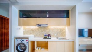 A compact kitchen with a washing machine, a sink, and a tiled backsplash. - Sweetome Boutique Apartment (Yangzhou Railway Station Jinghua City) (Yangzhou)
