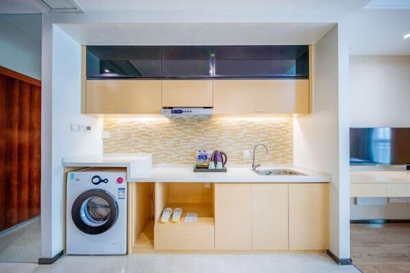 A compact kitchen with a washing machine, a sink, and a tiled backsplash. - Sweetome Boutique Apartment (Yangzhou Railway Station Jinghua City) (Yangzhou)
